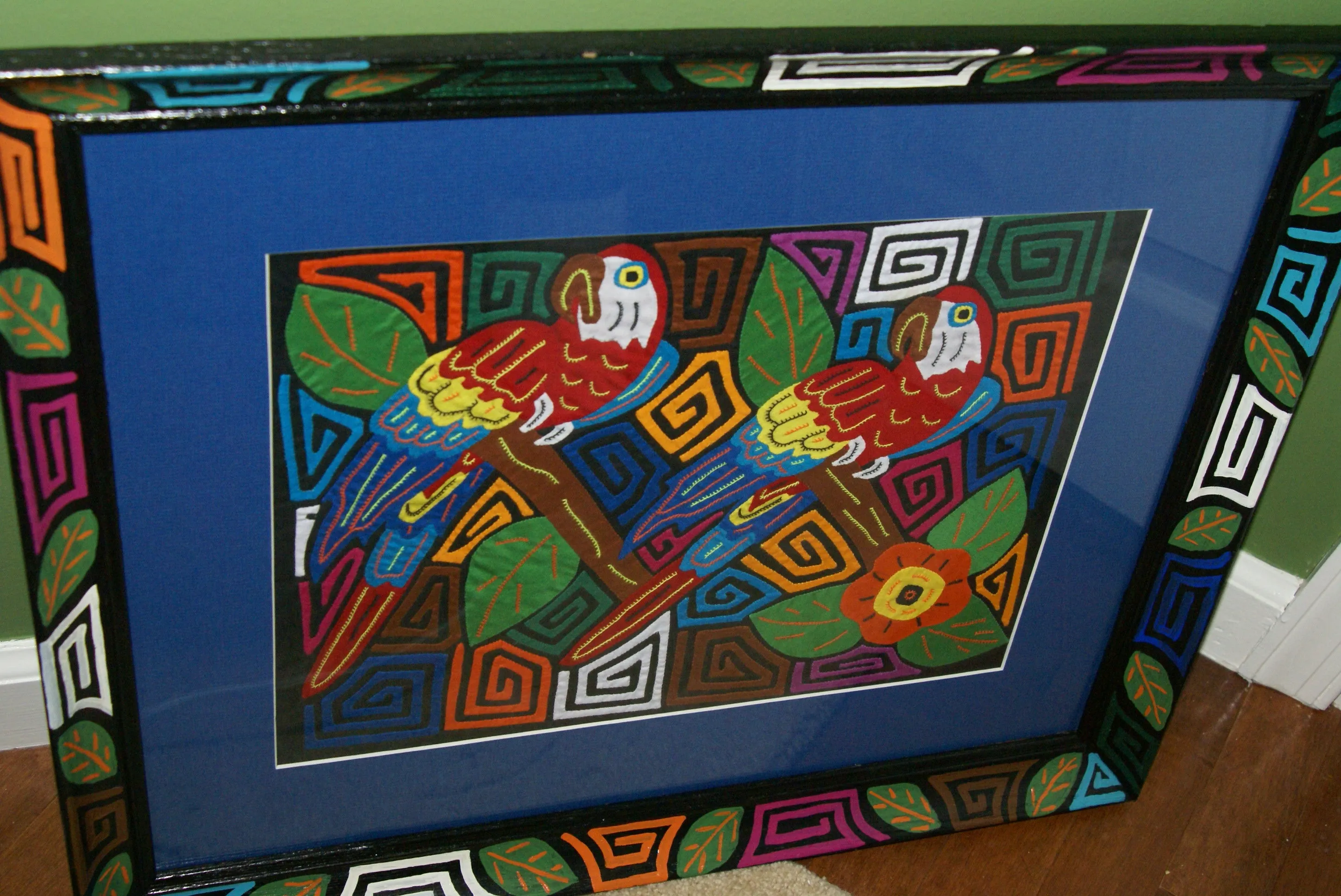 A Kuna Indian Folk Art Mola from San Blas Islands, in Custom Unique Hand Painted Signed Frame with  Blue Mat: Hand stitched Textile Applique: Colorful Macaw Parrot & Hibiscus Flowers, 23" x 18.5" (DFM19) Wall Decor