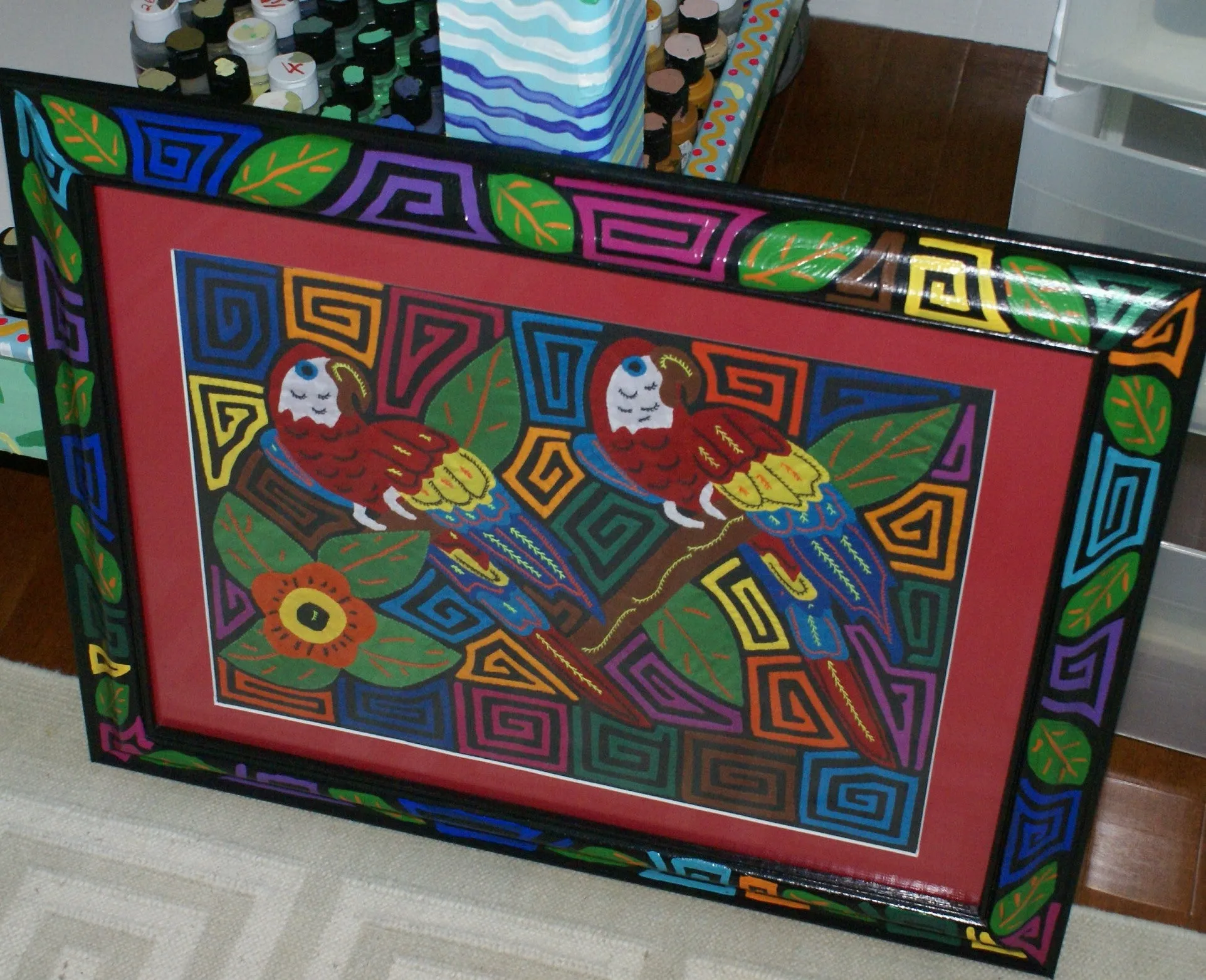 A Kuna Indian Folk Art Mola from San Blas Islands, in Custom Unique Hand Painted Signed Frame with red Mat: Hand stitched Textile Applique: Colorful Macaw Parrots & Hibiscus Flowers, 21.5" x 17" (DFM18) Wall Décor